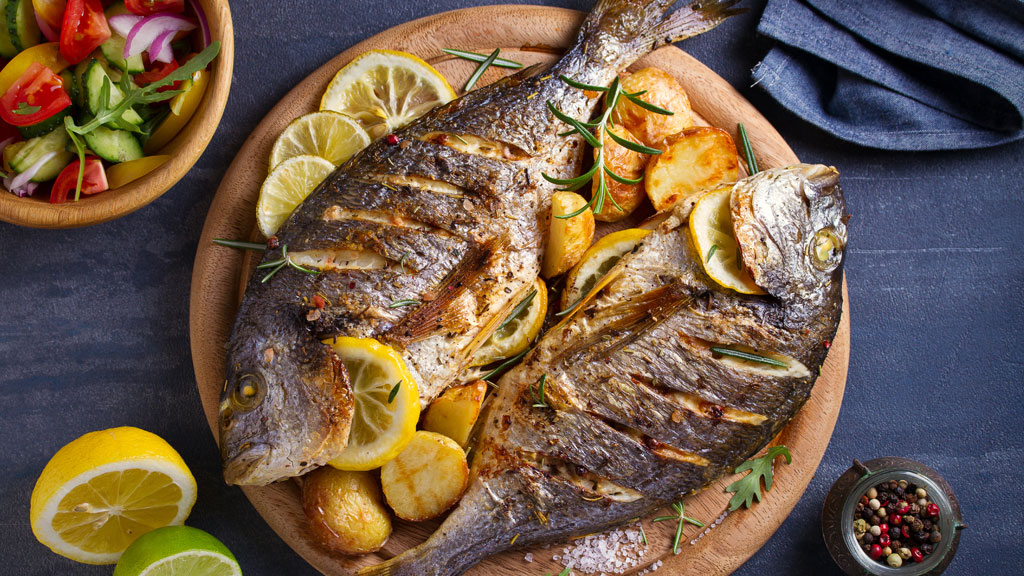 Chef dressant un plat de poisson du lac d'Annecy en cuisine professionnelle